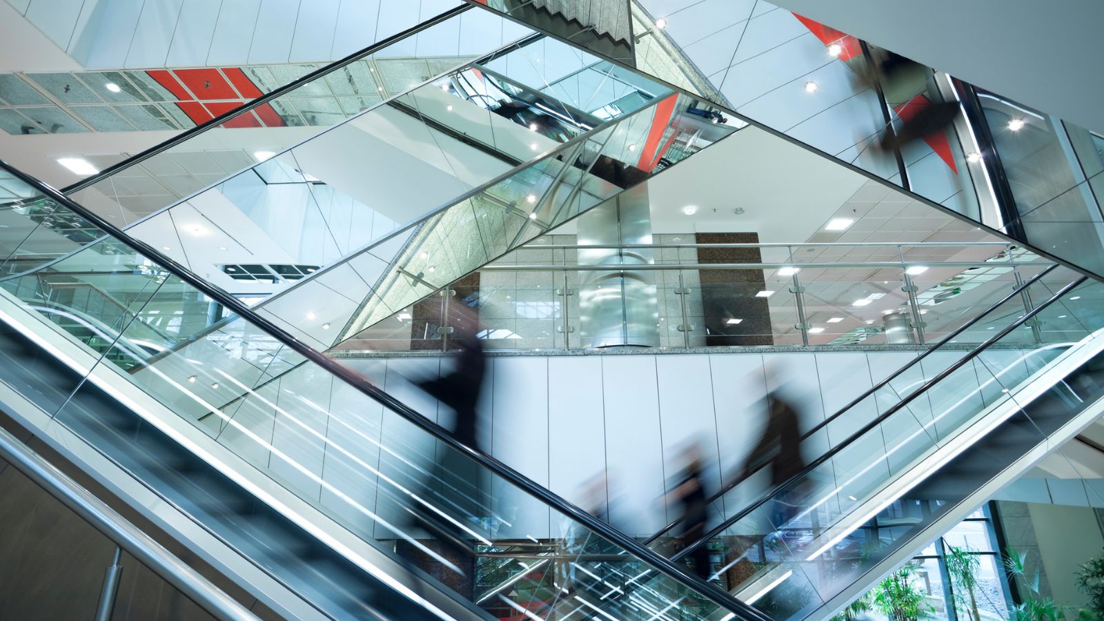 Blurred motion of people on escalators symbolizing complex workflow and process quality.