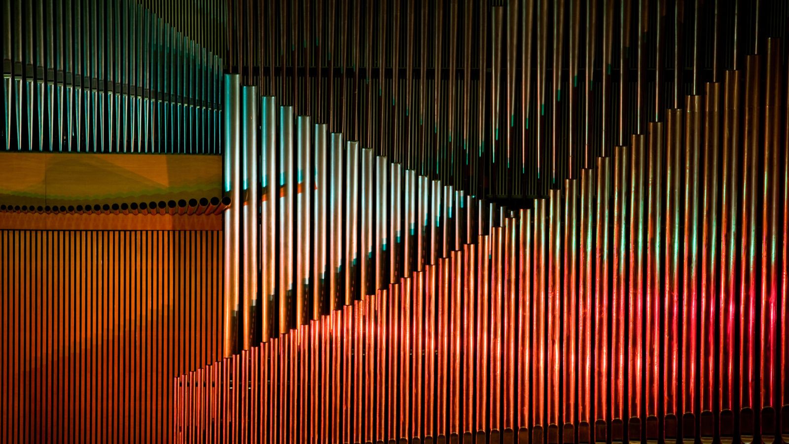 An arrangement of multiple modern organ pipes symbolizing the harmony and orchestration required to sync global brand messaging.