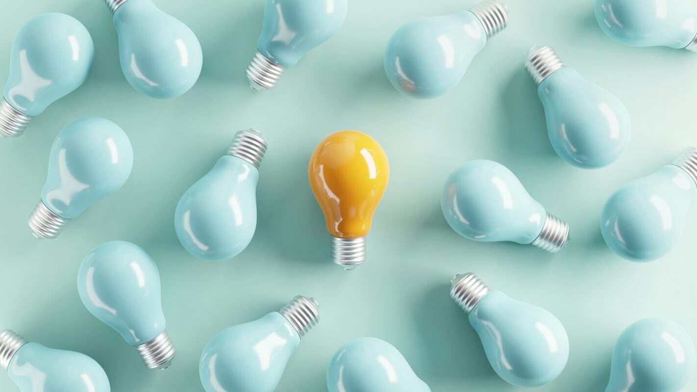 A single yellow light bulb standing out among blue bulbs representing the key decisions that shape an eLearning localization project